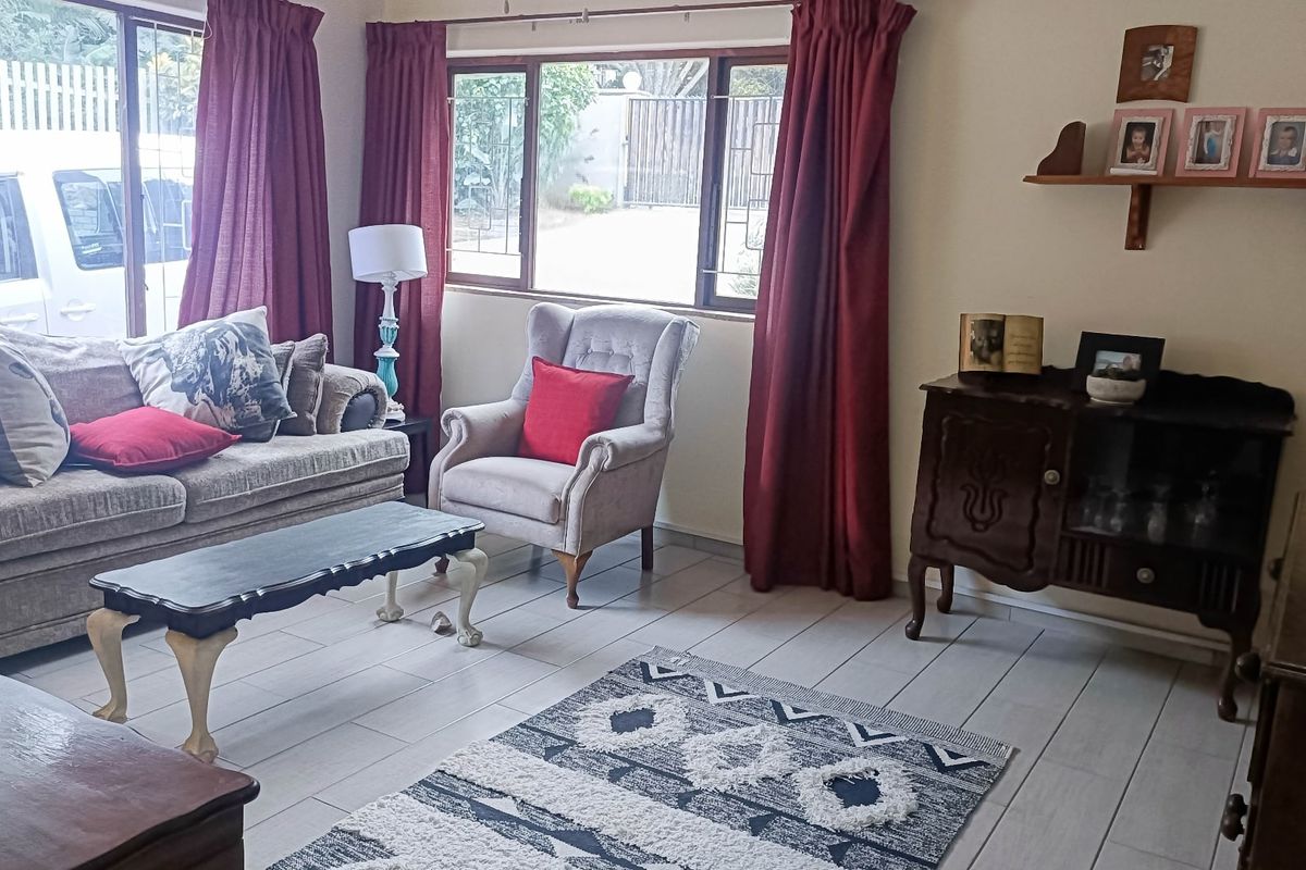 A comfortable living room featuring tiled flooring and large windows that provide natural light, creating a functional and inviting space.