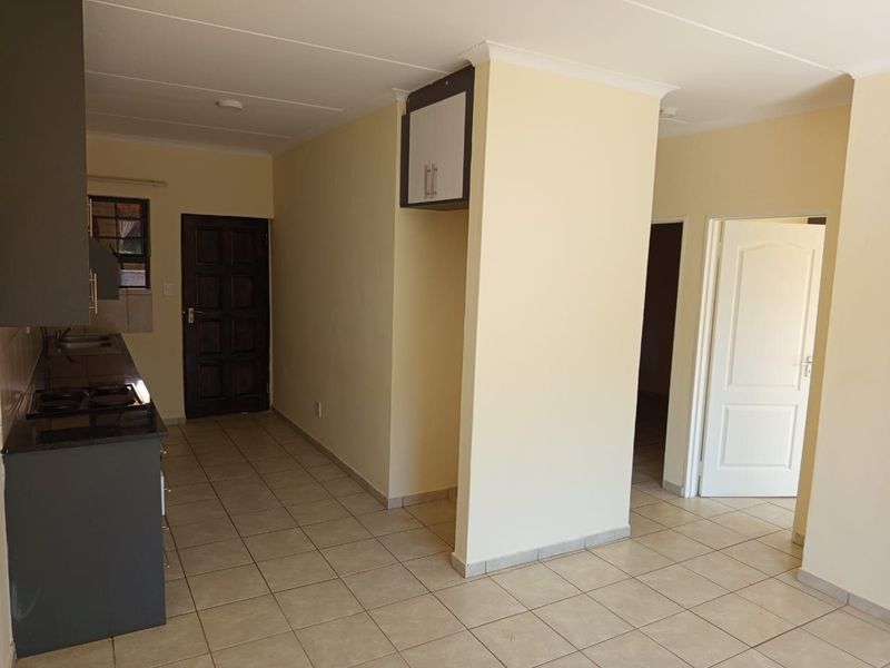 Open plan living area featuring tiled floors, a functional kitchen with granite countertops, gas hob, and neutral wall finishes throughout.