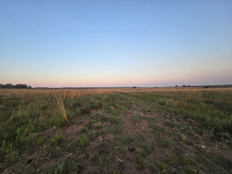 A wide-angle view of the expansive open farm landscape under a clear sunset sky.