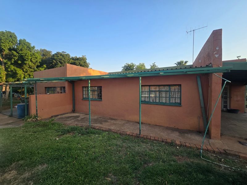 Rear exterior view of the farm dwelling featuring a covered patio area, steel-framed windows, and a metal roof structure.