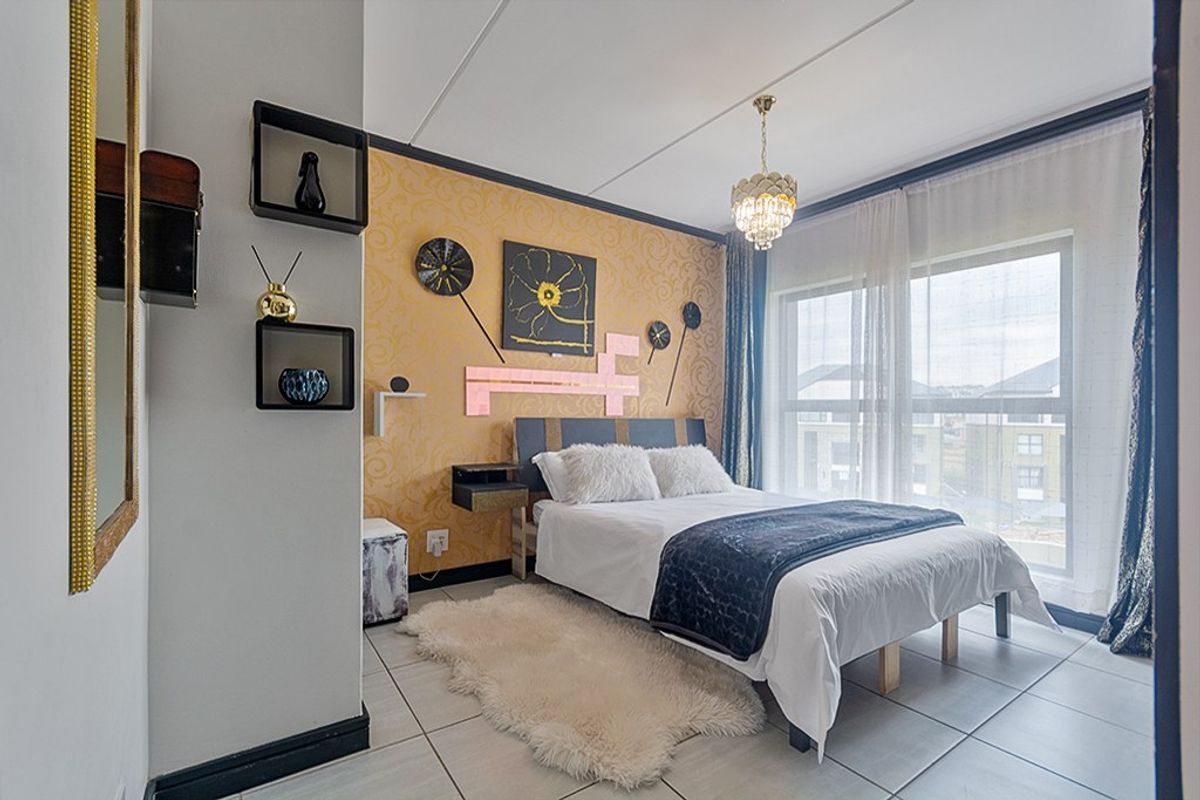 A bedroom featuring tiled flooring, a large window allowing natural light, and a decorative accent wall.