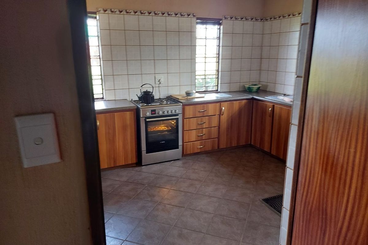 A functional kitchen featuring wooden cabinetry, tiled backsplash, tiled flooring, and a freestanding oven, offering a practical layout for daily meal preparation.