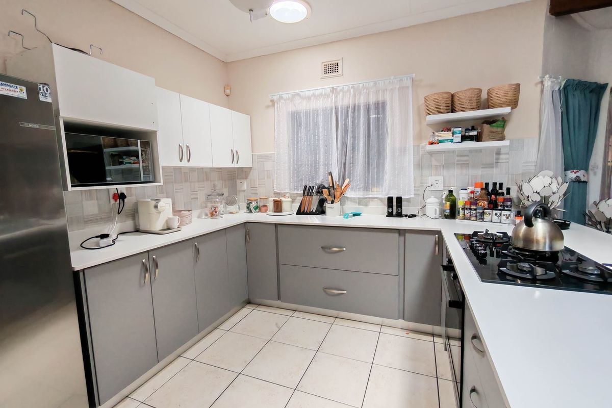 A functional kitchen featuring modern grey and white cabinetry, tiled flooring, a built-in gas hob, and ample counter space.