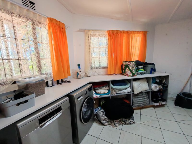 A functional laundry room featuring built-in cabinetry, tiled flooring, and integrated spaces for a washing machine and dishwasher.