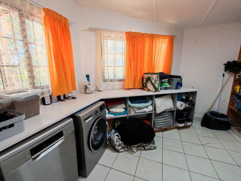 A functional laundry room featuring built-in cabinetry with integrated appliance spaces and tiled flooring.