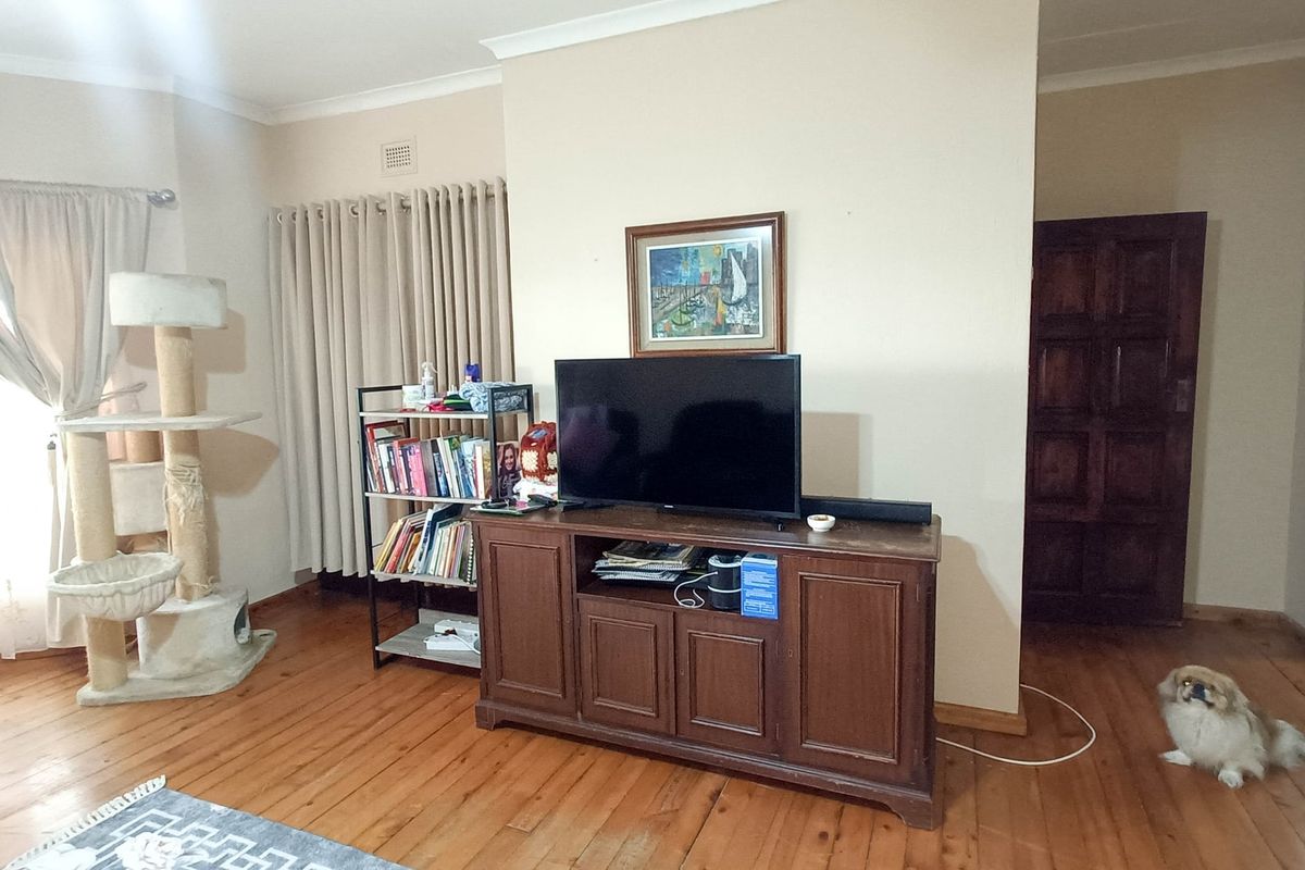 A living room featuring polished timber flooring, neutral wall tones, and a solid timber internal door, providing a warm and functional living space.