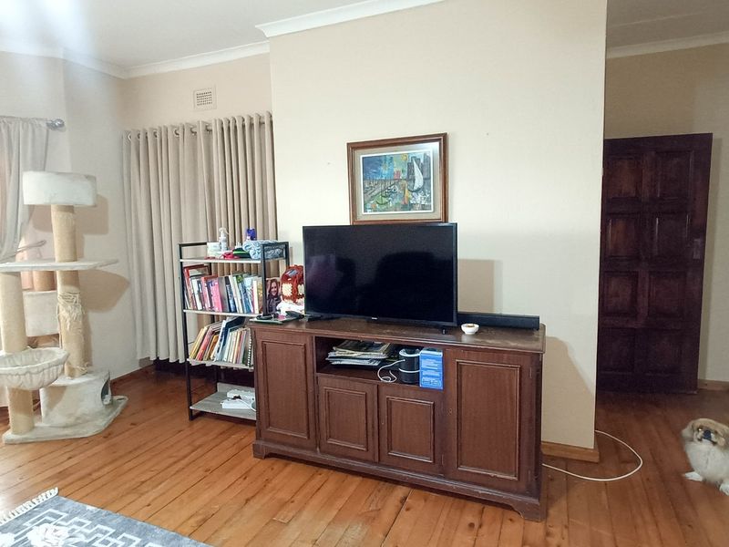A living room featuring polished timber flooring, neutral wall tones, and a solid timber internal door, providing a warm and functional living space.