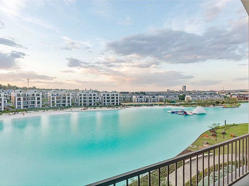 A scenic elevated view overlooking a large turquoise lagoon, landscaped estate grounds, and surrounding residential apartment buildings.