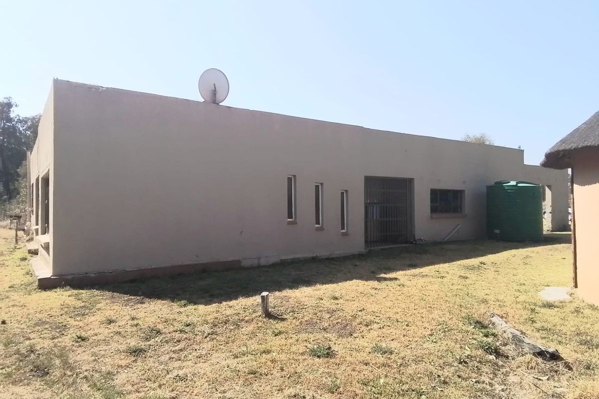 Rear exterior view of the property featuring plastered masonry walls, a security gate, and an external water storage tank.
