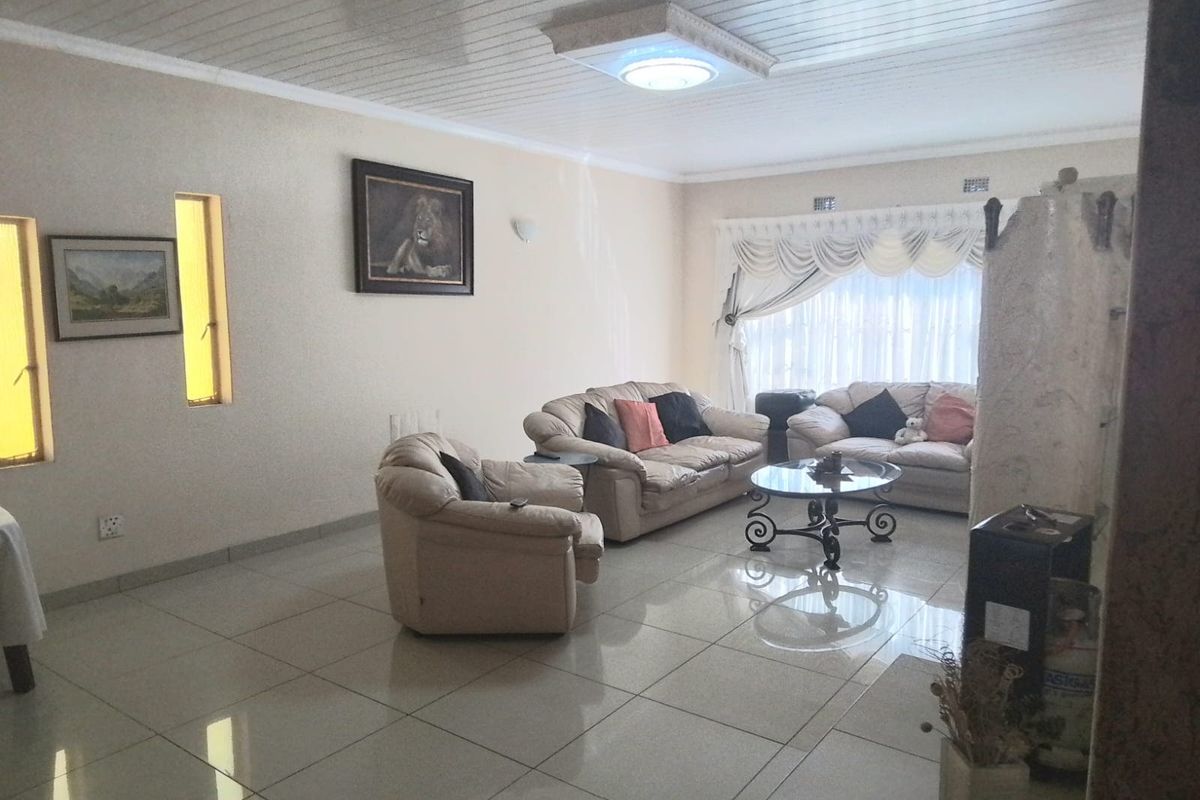 A spacious living room featuring large format floor tiles, a tongue and groove ceiling, and ample natural light from the window.