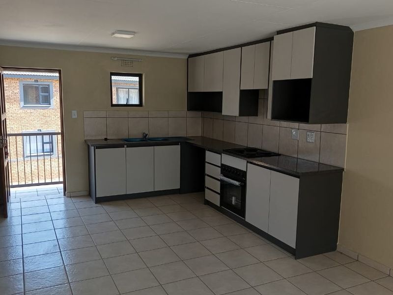 A functional kitchen featuring built-in cabinetry, a tiled backsplash, integrated oven and hob, and tiled flooring, with direct access to an exterior balcony.