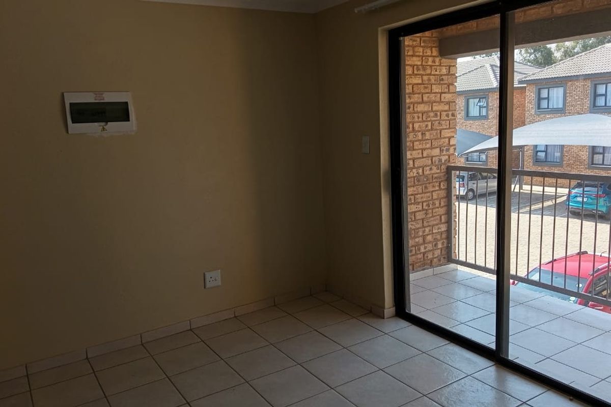 An empty living area featuring tiled flooring and a sliding glass door providing access to an outdoor balcony.