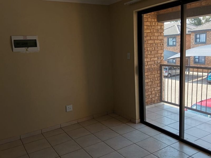 An empty living area featuring tiled flooring and a sliding glass door providing access to an outdoor balcony.