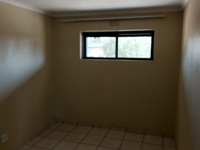 An empty bedroom featuring tiled flooring and a sliding window, providing a neutral space ready for personalization.