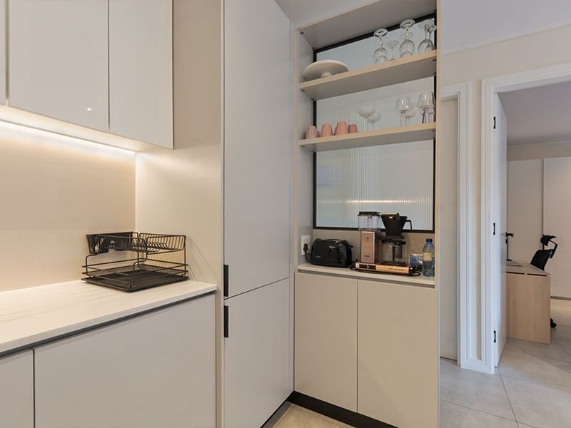 Modern kitchen featuring sleek handleless cabinetry, integrated shelving with fluted glass detailing, and ambient under-cabinet lighting.