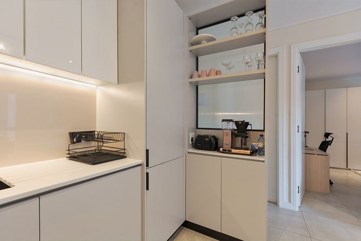 Modern kitchen featuring sleek handleless cabinetry, integrated shelving with fluted glass detailing, and ambient under-cabinet lighting.