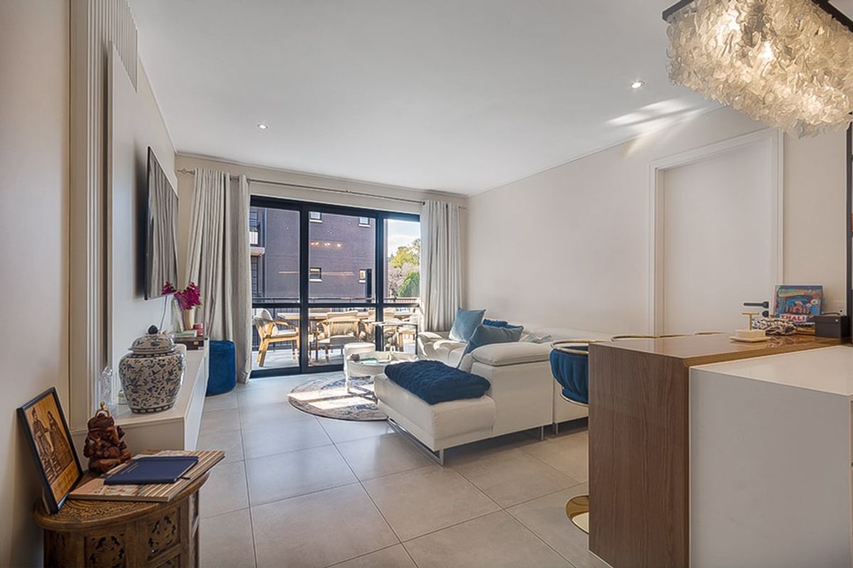Modern open-plan living area featuring tiled floors, recessed lighting, and seamless access to an outdoor balcony through large sliding glass doors.