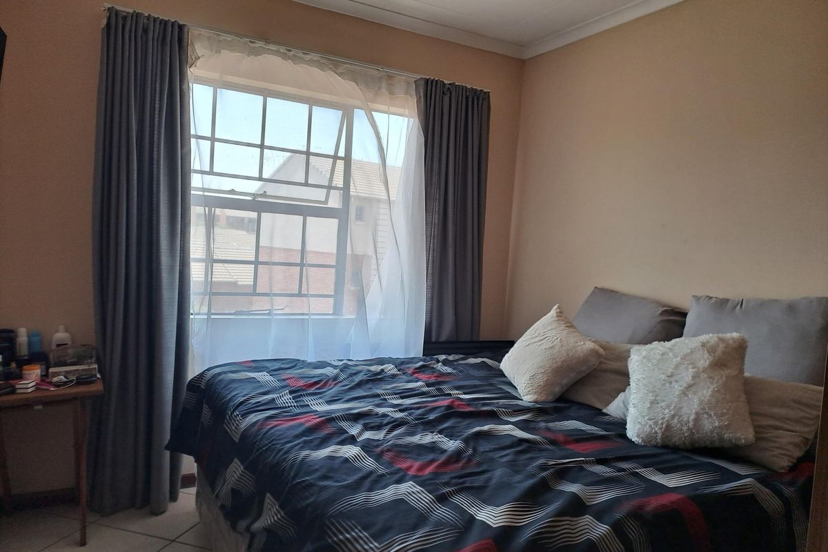 A functional bedroom featuring tiled flooring, coving, and a sash window allowing natural light into the space.