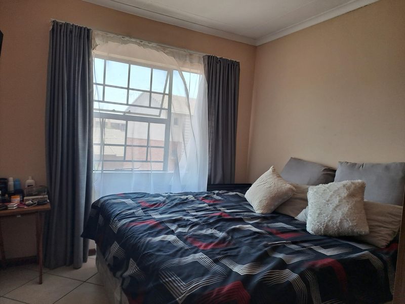 A functional bedroom featuring tiled flooring, coving, and a sash window allowing natural light into the space.