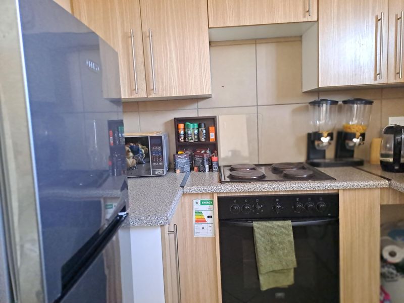 Compact kitchen featuring light wood-finish cabinetry, granite-look laminate countertops, a built-in electric oven, and a hob with a tiled splashback.