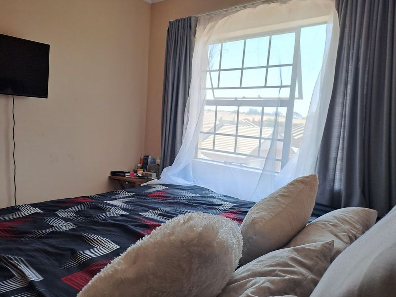 A bedroom featuring a large sash window with curtain tracks, providing natural light and a view of the surrounding neighborhood.
