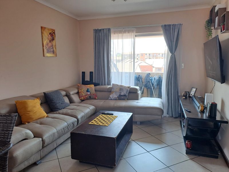 A comfortable living room featuring tiled flooring and a sliding glass door that provides access to an outdoor balcony area.