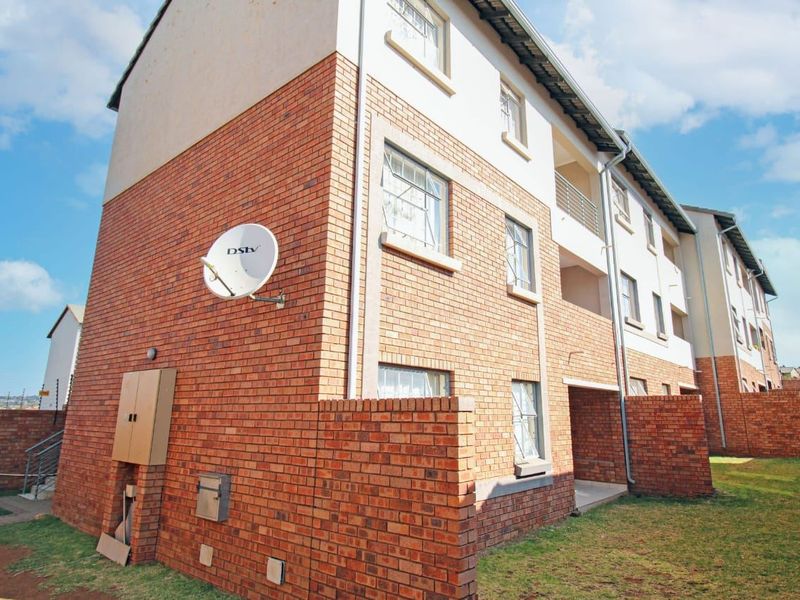 Rear view of a multi-story apartment building featuring face brick construction, balconies, and integrated utility services.
