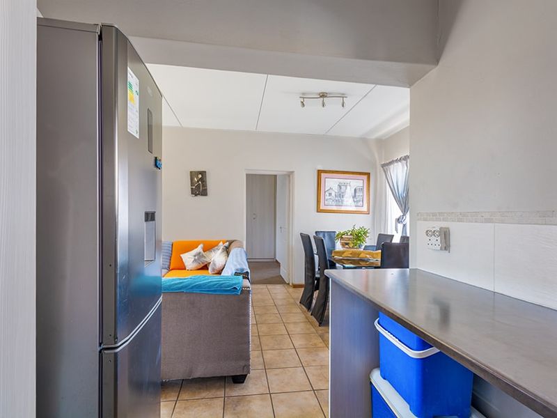 Open plan living and dining area featuring tiled flooring and a functional kitchen workspace with a tiled backsplash.