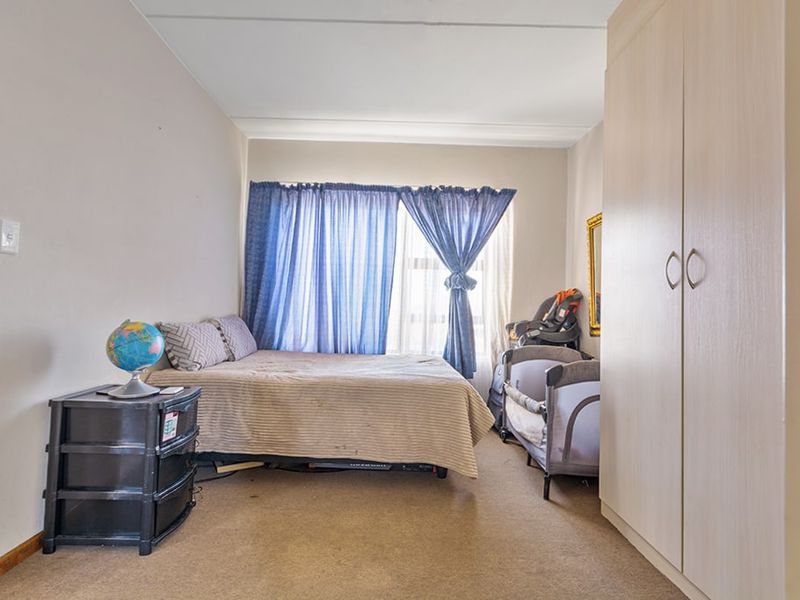A functional bedroom featuring a built-in wardrobe and carpeted flooring, offering a practical layout for comfortable living.