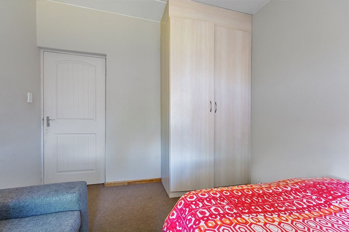 A bedroom featuring neutral walls, carpeted flooring, and a light wood-finish built-in wardrobe.
