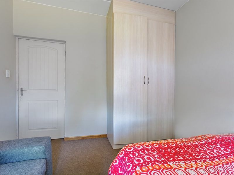 A bedroom featuring neutral walls, carpeted flooring, and a light wood-finish built-in wardrobe.