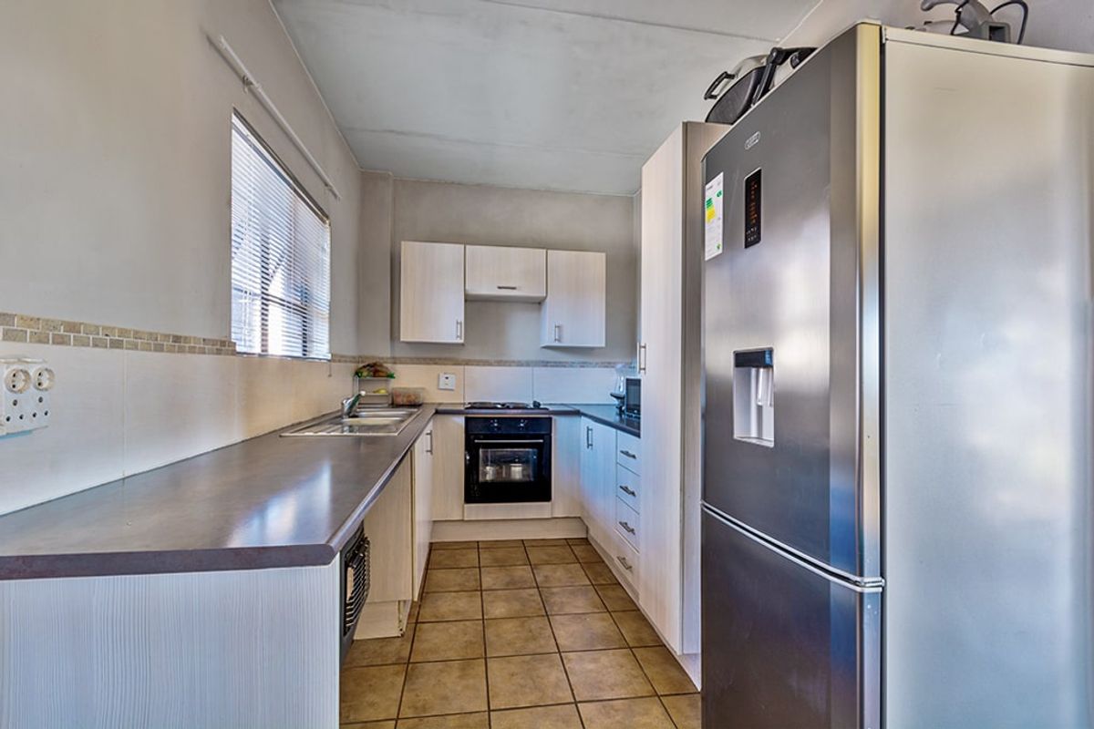 A functional kitchen featuring built-in cabinetry, laminate countertops, a tiled backsplash, and integrated cooking appliances with tiled flooring throughout.