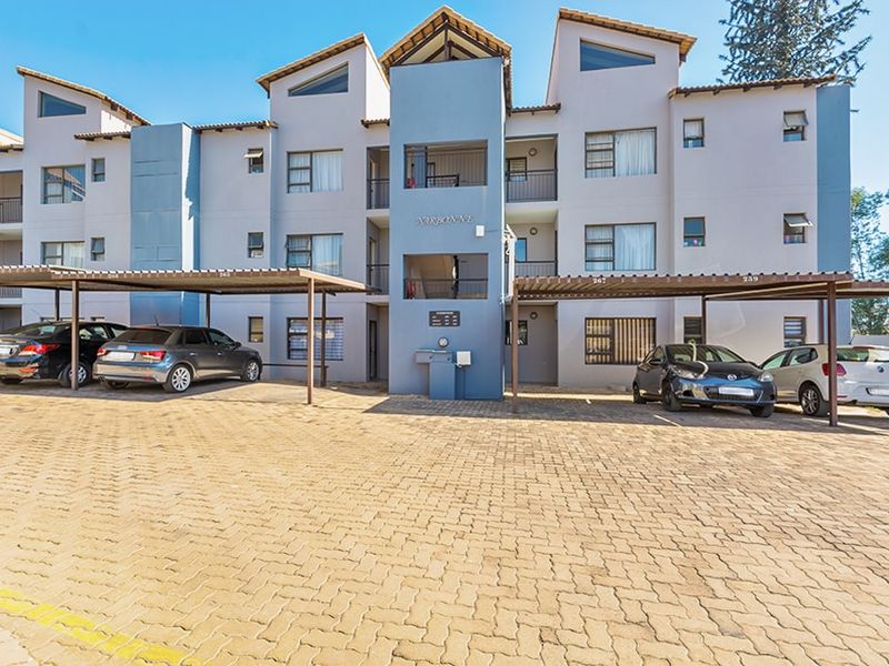 Front elevation of the Narbonne apartment complex featuring paved parking area with covered bays and multi-story residential units.