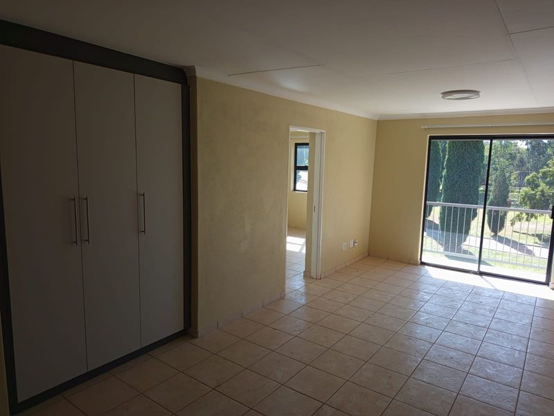 An empty bedroom featuring tiled flooring, a built-in wardrobe, and a sliding glass door providing access to a balcony.
