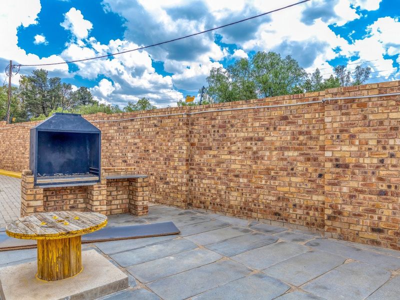 Outdoor patio area featuring a built-in braai and high brick boundary walls, providing a private space for outdoor entertainment.
