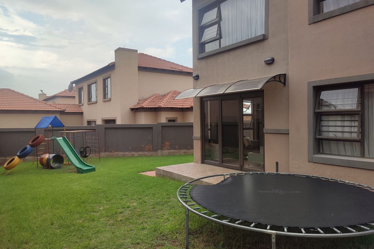 Rear view of the townhouse featuring a small tiled patio, sliding glass doors, and a private garden area with perimeter walling.