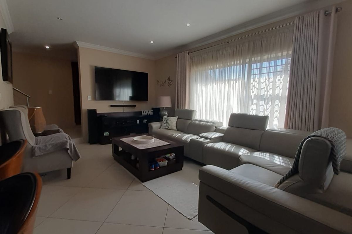 Spacious living room featuring neutral tiled flooring, recessed downlighting, and large sliding glass doors that provide ample natural light.