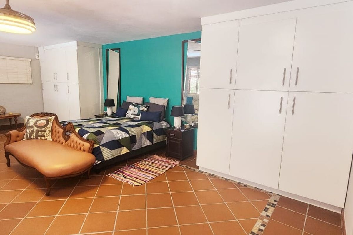 Spacious bedroom featuring extensive built-in cabinetry, tiled flooring, and a vibrant accent wall, offering ample storage and a functional layout.