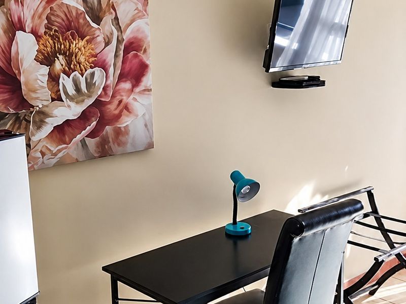 A bedroom area featuring tiled flooring, coving, and a wall-mounted television.