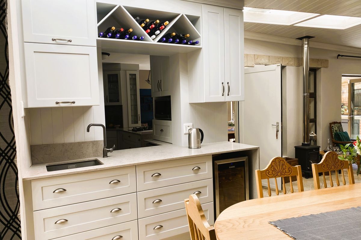 Modern kitchen area featuring white cabinetry, stone countertops, integrated wine storage, and a cozy wood-burning stove with overhead skylights.