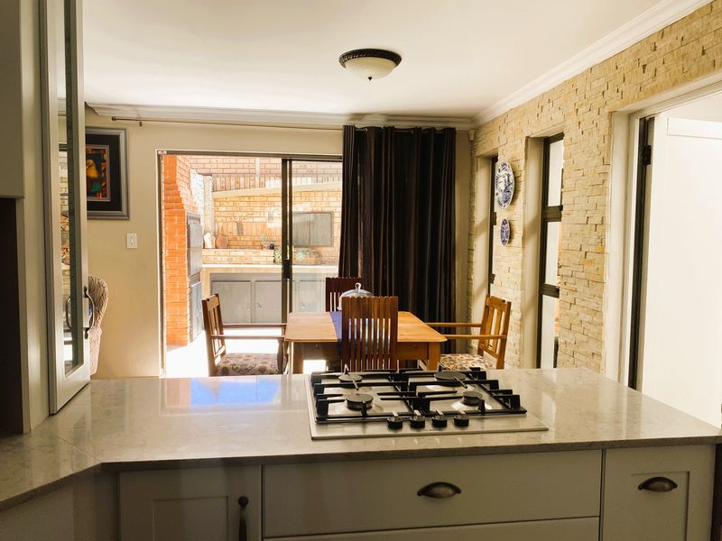 Open plan kitchen and dining area featuring a gas hob, stone veneer wall, and direct access to the outdoor patio through sliding glass doors.