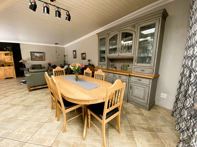 Spacious open-plan dining and living area featuring tiled flooring, a classic beadboard ceiling, and a large built-in hutch for display and storage.