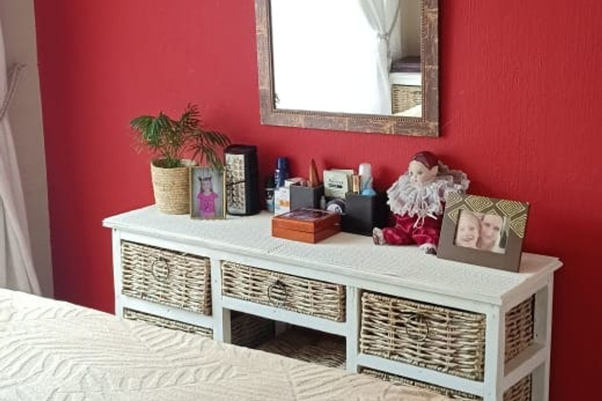 A bedroom featuring tiled flooring and a bold red accent wall, providing a functional space for rest.