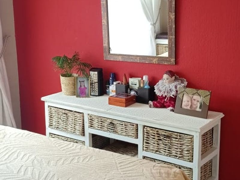 A bedroom featuring tiled flooring and a bold red accent wall, providing a functional space for rest.