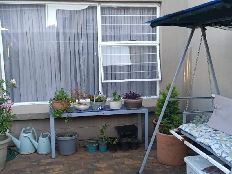A paved patio area featuring a window with security bars, providing a functional outdoor space for relaxation.