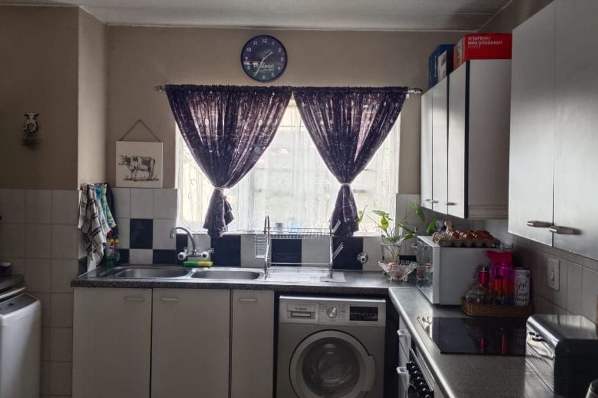 Functional kitchen featuring built-in cabinetry, double sink, electric hob, and integrated laundry appliance with tiled splashback.