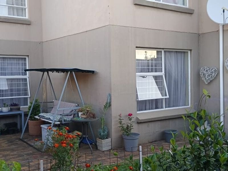 Ground floor apartment exterior featuring a paved patio area, security bars on windows, and exterior wall plastering.