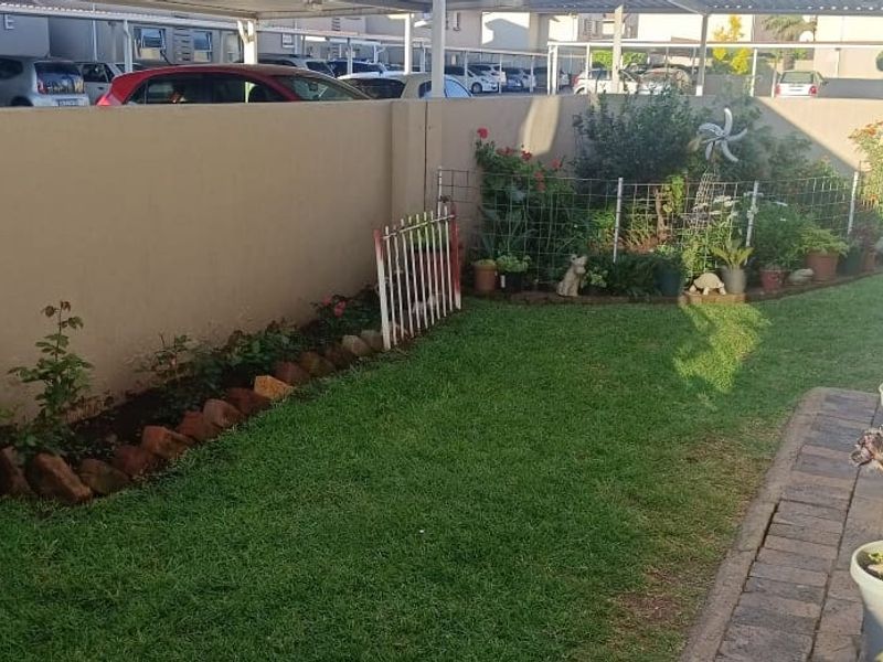 A private garden area featuring a well-maintained lawn, perimeter wall, and paved walkway, providing a pleasant outdoor space for the apartment.