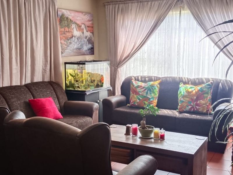A comfortable living room area featuring tiled flooring and a large sliding glass door providing natural light.