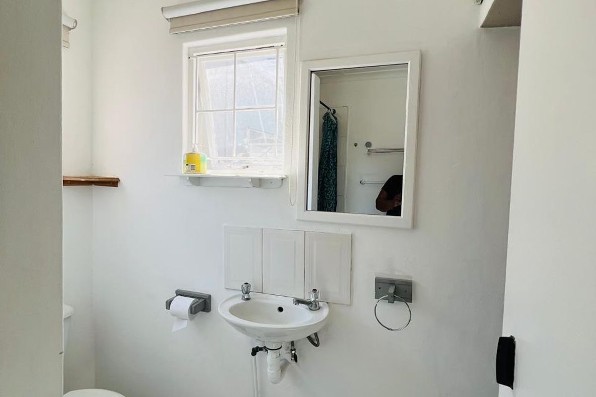 A compact bathroom featuring a wall-mounted basin, toilet, and classic black and white checkered floor tiles.